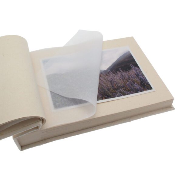 An open Elephant Dung Photo Album shows a translucent protective sheet partially covering a landscape photo of purple flowers and mountains.