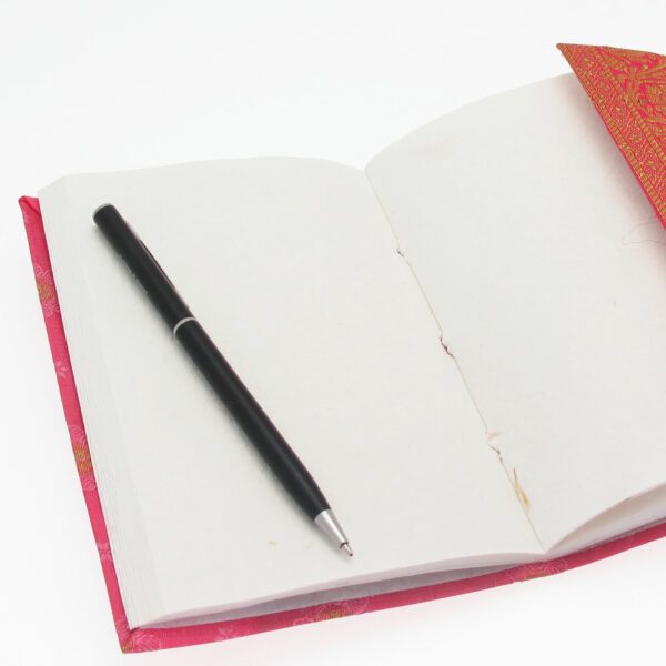 Open a medium-sized Sari Fabric Notebook with blank pages and a black pen on top.