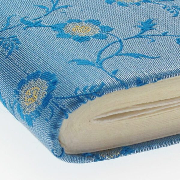 A close-up of the Extra Large Sari Fabric Photo Album featuring a blue cover with yellow and blue embroidered flowers. The thick, slightly uneven pages add to its handcrafted charm.