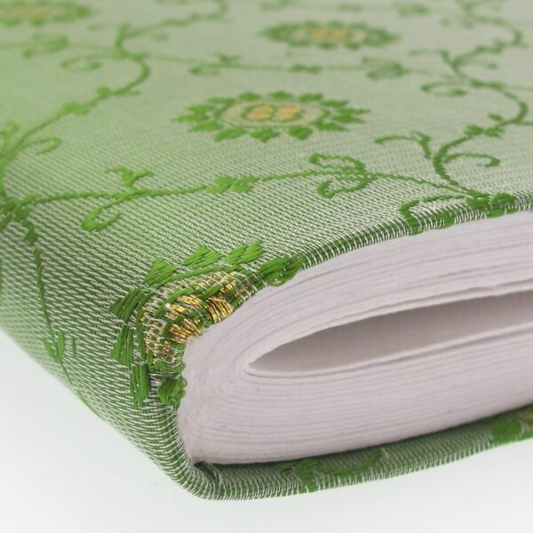 A close-up of a Medium Sari Fabric Photo Album with white pages and a green cover adorned with embroidered floral patterns and gold accents.