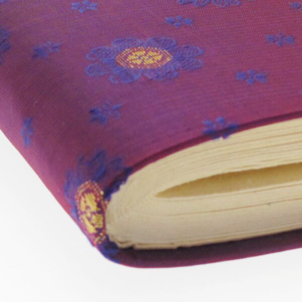 A close-up of the Small Sari Fabric Photo Album, featuring a purple cover with yellow and blue floral patterns, and showing the edge of its pages.