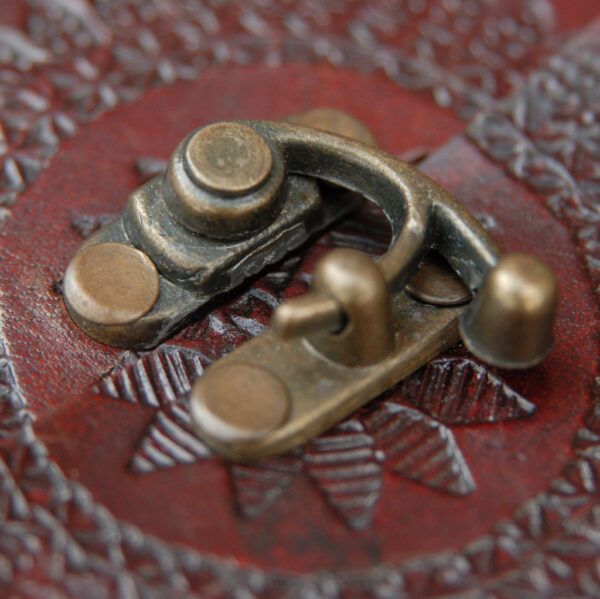 Close-up of a metal latch on the Indra A4 Embossed Leather Journal, featuring a textured brown surface adorned with a star-shaped pattern.