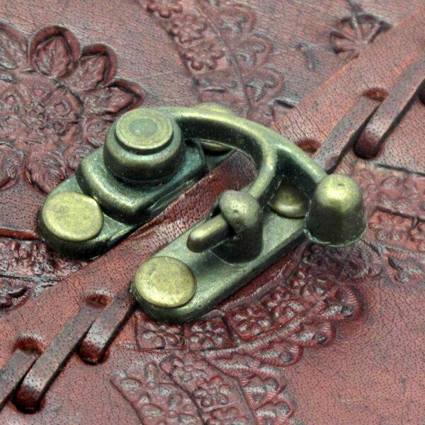 Close-up of an ornate brass latch on the cover of the Indra Medium Embossed & Stitched Leather Journal, featuring floral embossing.