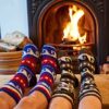 Two people wearing hand knitted, fair trade Woollen Annapurna Socks in front of a fireplace.