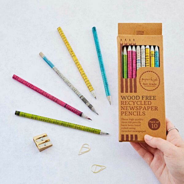 A hand holds a box of "Recycled Newspaper Pencils" with seven pencils and a sharpener, all displayed on a white background.