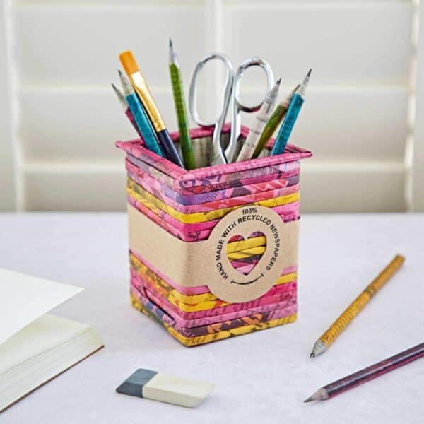 A Square Recycled Newspaper Pencil Holder contains various pens, pencils, paintbrushes, and scissors. A label proudly reads "100% handmade with recycled newspapers.
