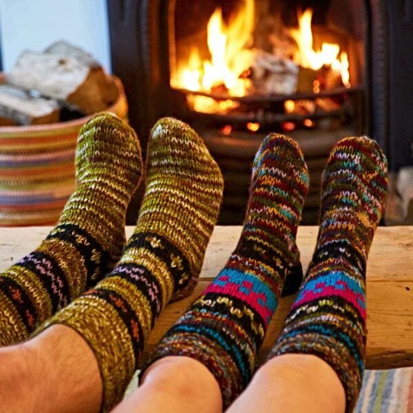 Two people wearing fair trade Woollen Annapurna Socks in front of a fireplace.
