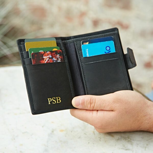 A person holds an open Buffalo Leather Wallet with cards visible in several slots and the initials "PSB" embossed in gold on the front pocket.