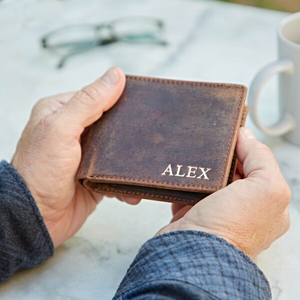 A man holding a Personalised Buffalo Leather Billfold Wallet with the name alex on it.