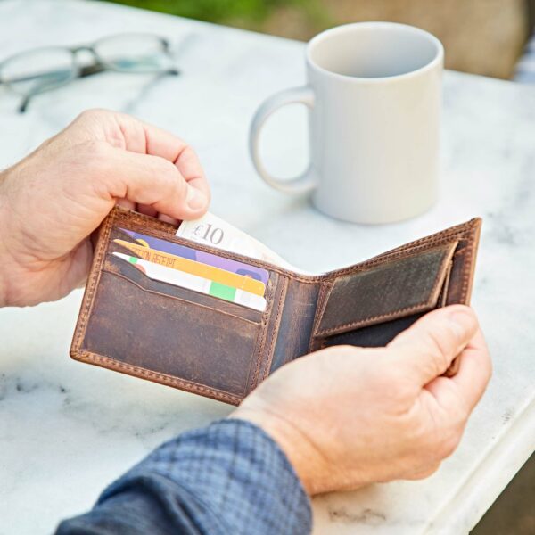 A man holding a Personalised Buffalo Leather Billfold Wallet and a cup of coffee.