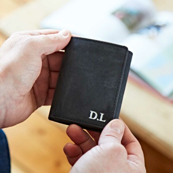 Someone holds a Personalised Buffalo Leather Trifold Wallet with the initials "D.L" embroidered in white on its corner.