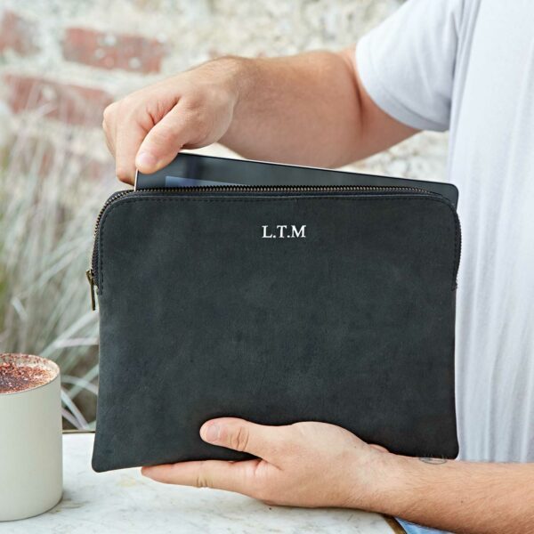 A person places a tablet into a black zip-fastened Buffalo Leather Tablet Case with the initials "L.T.M" embossed on it.