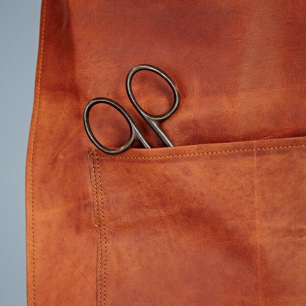 A pair of metal scissors peeking from the front pocket adds character to the Personalised Brown Leather Apron.
