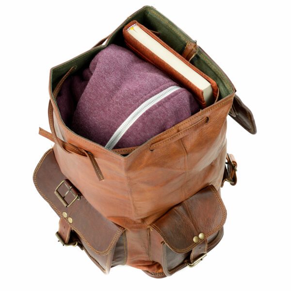 An eco-friendly Personalised Large Brown Leather Rucksack holds a folded purple sweatshirt and a closed notebook.