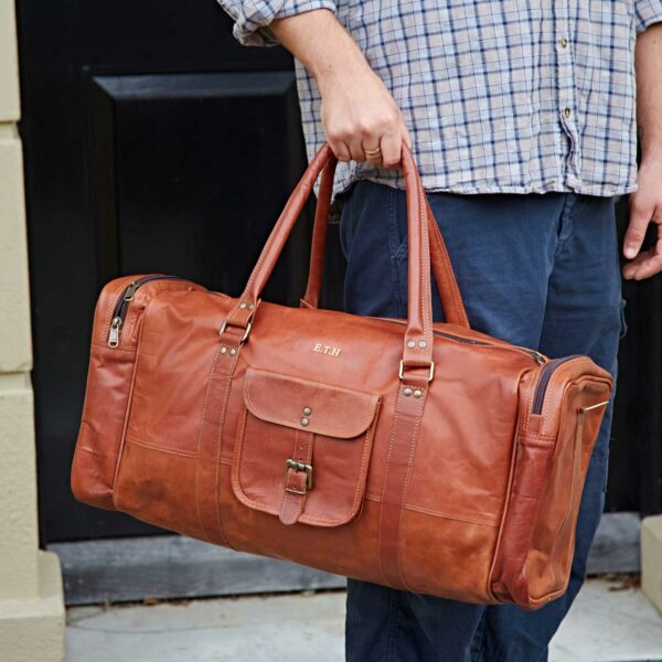 A man is holding a personalized leather holdall.
