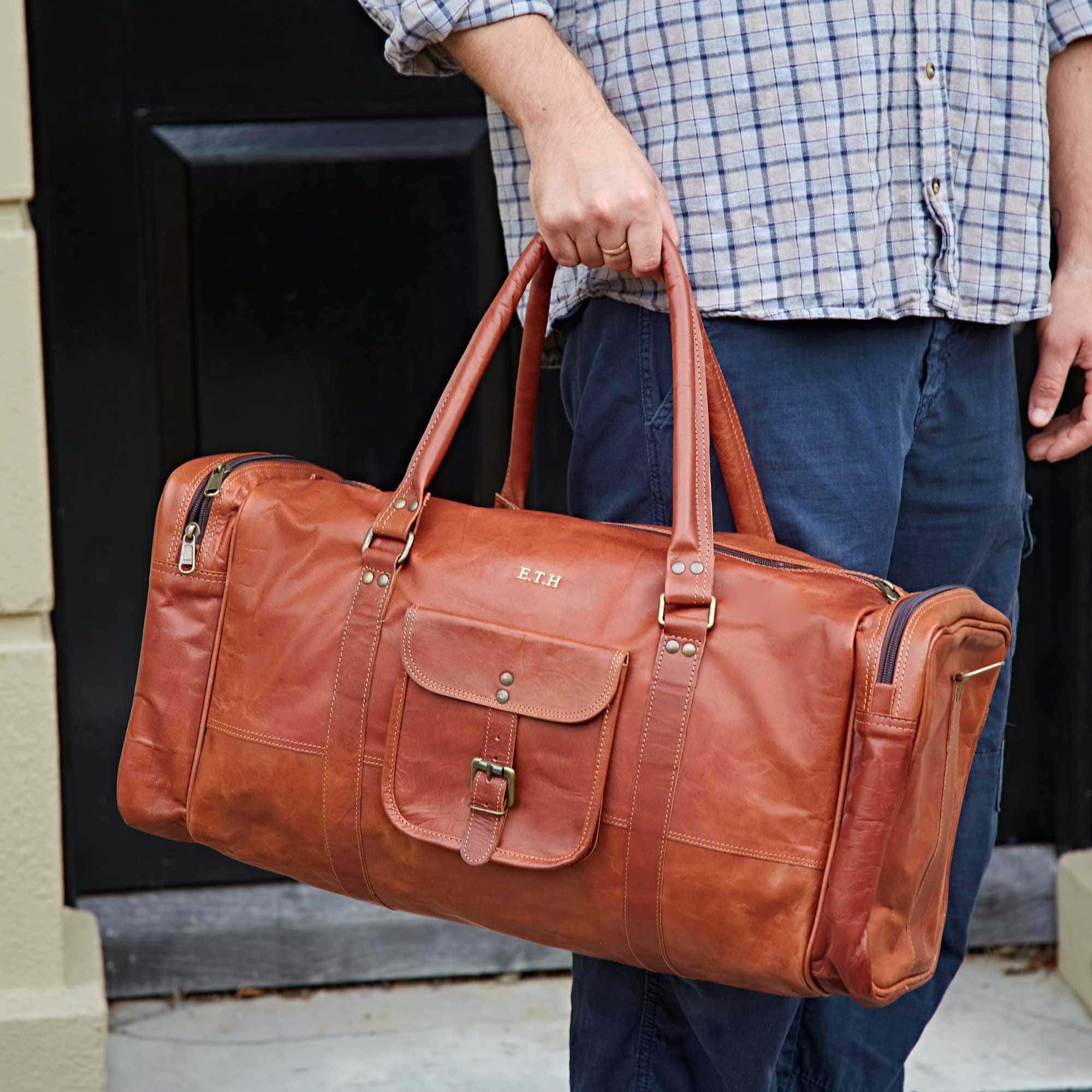 A man is holding a personalized leather holdall.