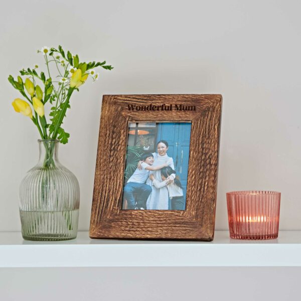 A Personalised Natural Mango Wood Photo Frame next to a vase of flowers.