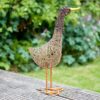 Jiro the Standing Duck Wire Garden Ornament, crafted from woven wire, stands gracefully on a wooden decking surrounded by lush greenery.