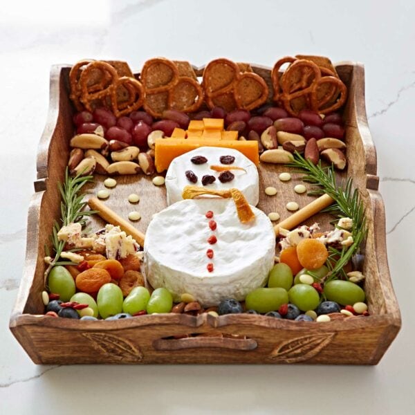 A Natural Mango Wood tea tray with cheese shaped like a snowman, grapes, nuts and pretzels.