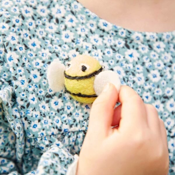 A little girl holding a Pack of 3 Felt Bee Brooches.