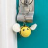 A Felt Bee Keyring hangs on a blue door.