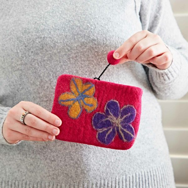 A person in a gray sweater holds a Felt Flower Purse adorned with two designs in yellow and purple.