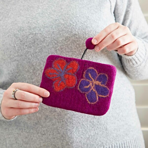 Person holding a Felt Flower Purse with orange and purple flower designs, secured with a string and a button.