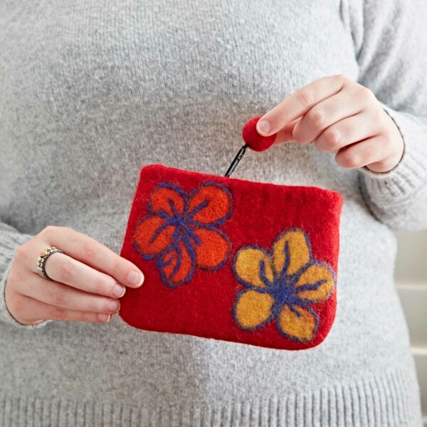 A person in a grey sweater holds a Felt Flower Purse adorned with orange and yellow floral designs.