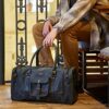 A man sitting on a bench with a Customizable Leather Holdall with Zippered Pockets.