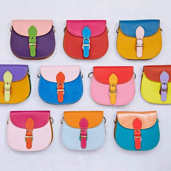 Ten vibrant leather handbags, such as the Multicoloured Saddle Crossbody Bag, feature buckle closures and are artfully arranged in a grid against a light background.