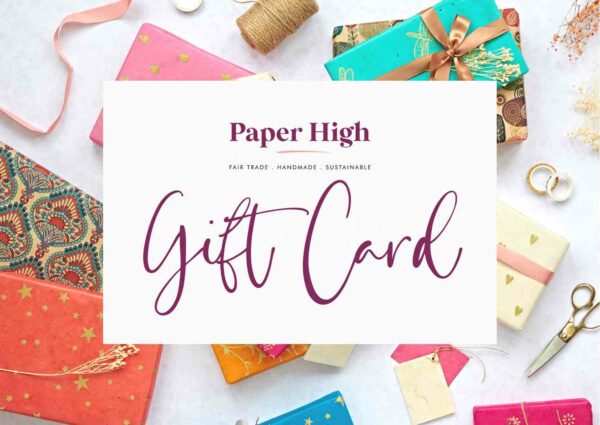 A Gift Card is displayed on a light surface, surrounded by colourful wrapped presents, ribbons, scissors, and string for a festive look.