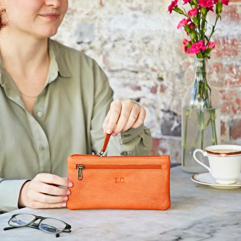 A woman sitting at a table with a Personalised Leather Clutch Purse.