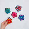 A hand delicately presents a Felt 4 Flower Hair Band against a pristine white background.