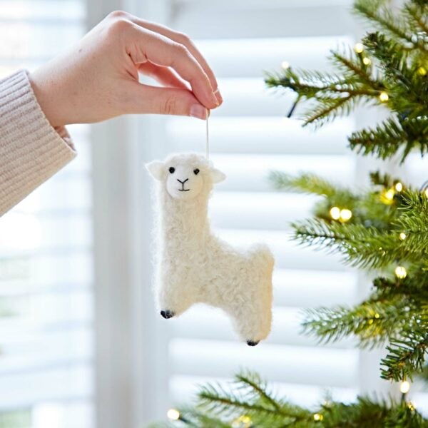 A person holding a Felt Alpaca Christmas Decoration on a Christmas tree.
