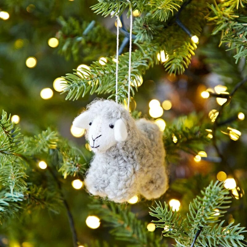 A Felt Sheep Christmas Decoration hangs from a tree.