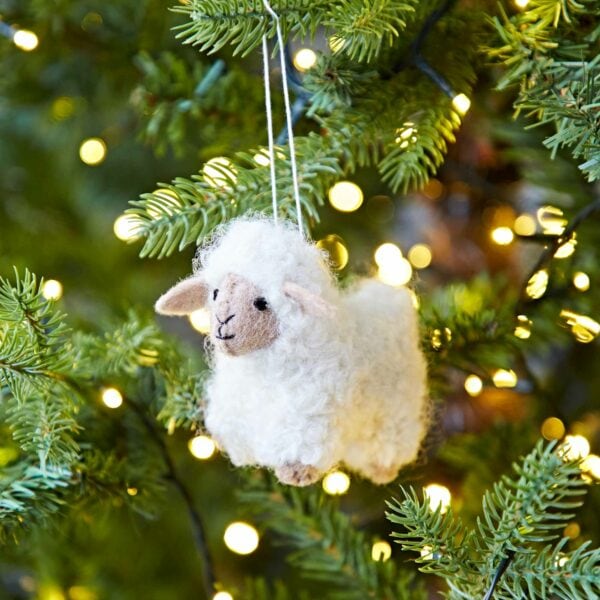 A Felt Sheep Christmas Decoration hangs from a Christmas tree.