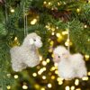 Two Felt Sheep Christmas Decorations hanging from a tree.