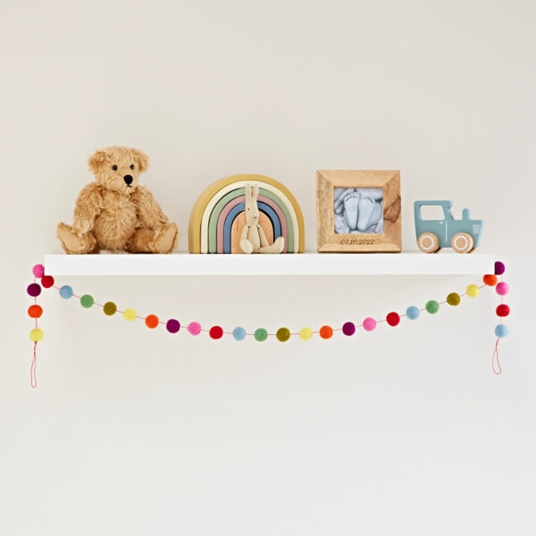 A handmade Multicoloured Felt Ball Garland adorned with a teddy bear.