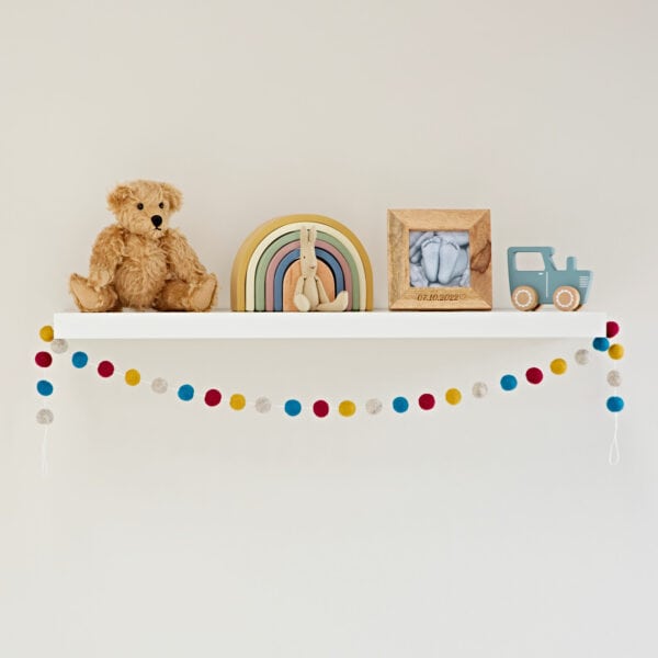 A Handmade Multicoloured Felt Ball Garland adorned with a cute teddy bear and pom poms.