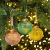 Three Ira Glass Baubles hanging from a Christmas tree.