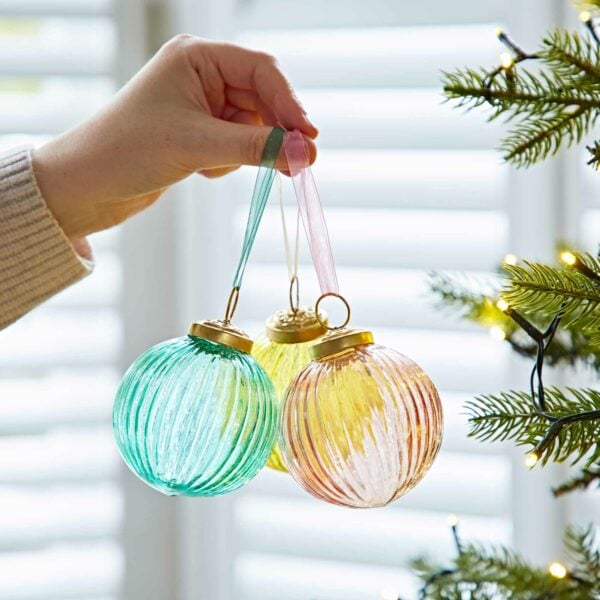 Three Ira Glass baubles hanging from a Christmas tree.