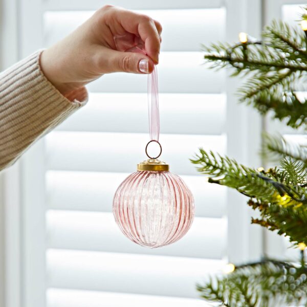 Ira Glass holding a pink bauble on a Christmas tree.