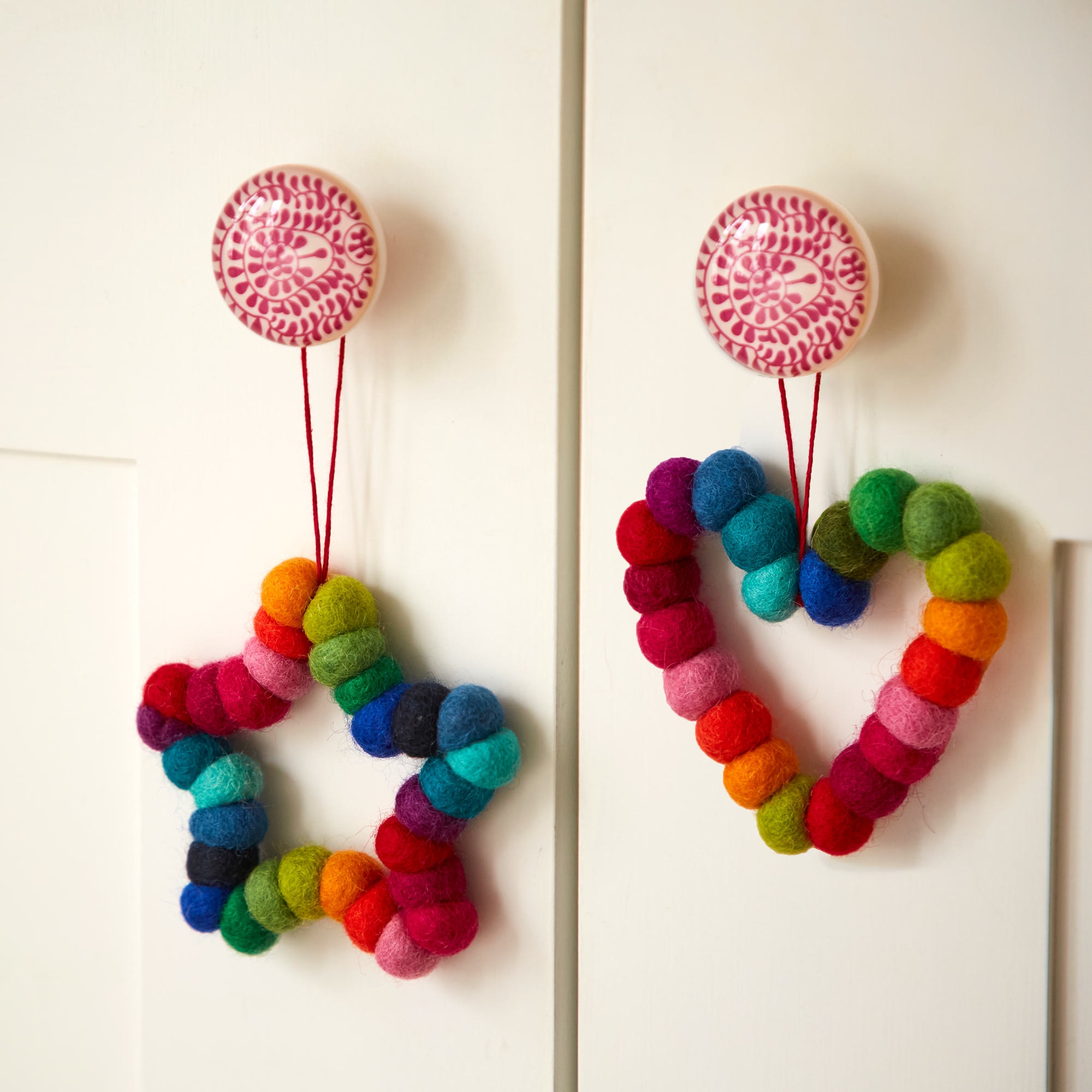 Two Felt Multicoloured Decorations hanging on a door.