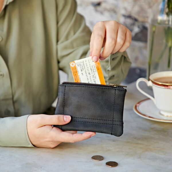 A woman is holding a black wallet with a credit card in it made of Buffalo Leather.