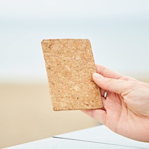 A person holding a piece of cork on a Natural Cork Sliding Credit Card Holder on a beach.