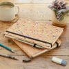 A Natural Cork A5 Notebook with a pen and pencil on a wooden table