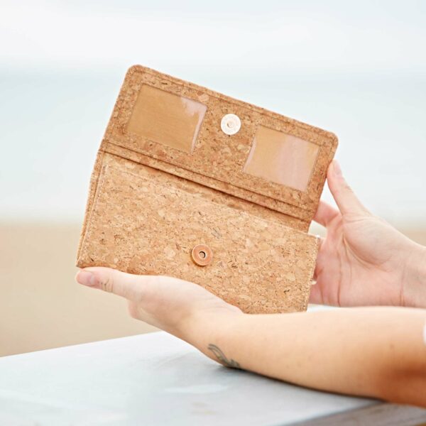 A woman holding a personalised Natural Cork Clutch Purse on the beach.