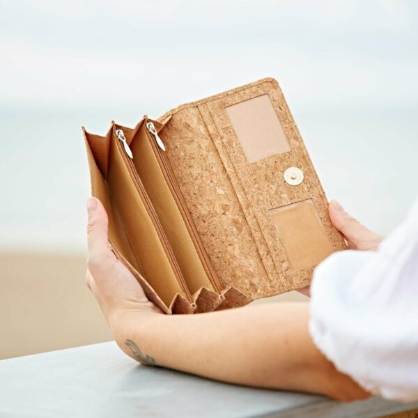 A woman holding a personalised Natural Cork Clutch Purse on the beach.