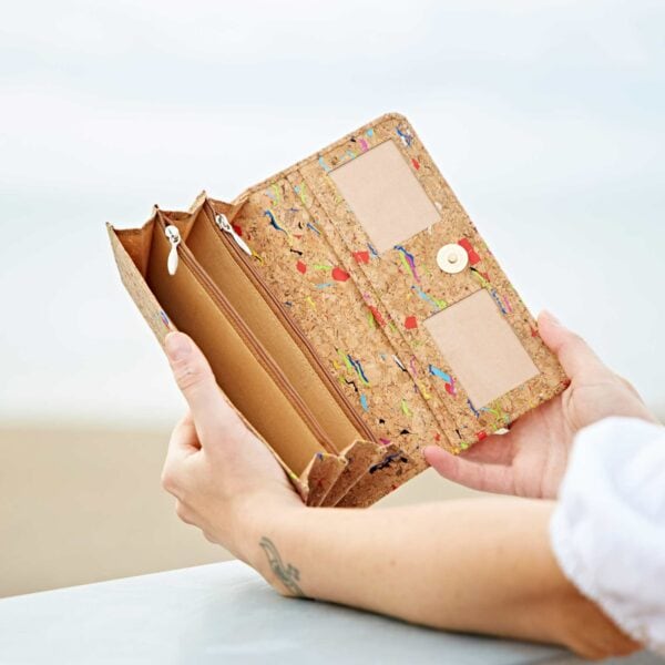 A woman holding a Natural Cork Clutch Purse on the beach.