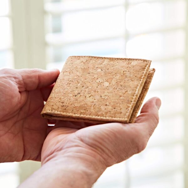 A Natural Cork Billfold Wallet securely grasped by a man's hand.